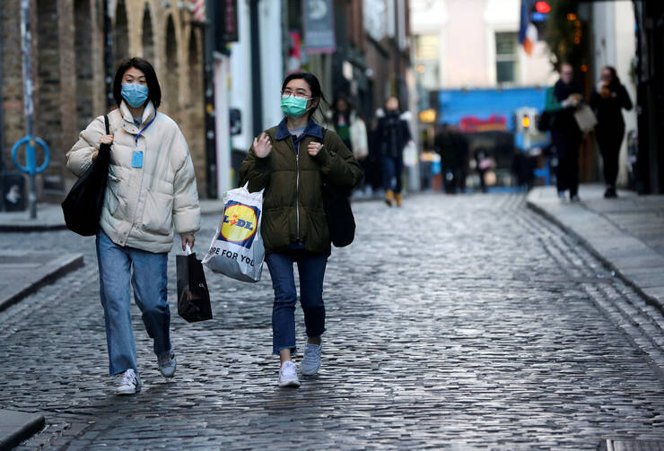 Tourists in Dublin walk with face masks to curb the spread of coronavirus on March 15, 2020. With all St. Patrick's Day parades and events canceled due to restrictions aimed at containing the coronavirus pandemic, most bishops and priests celebrated St. Patrick's Day Masses via webcam or parish radio. (CNS photo/Lorraine O'Sullivan, Reuters)