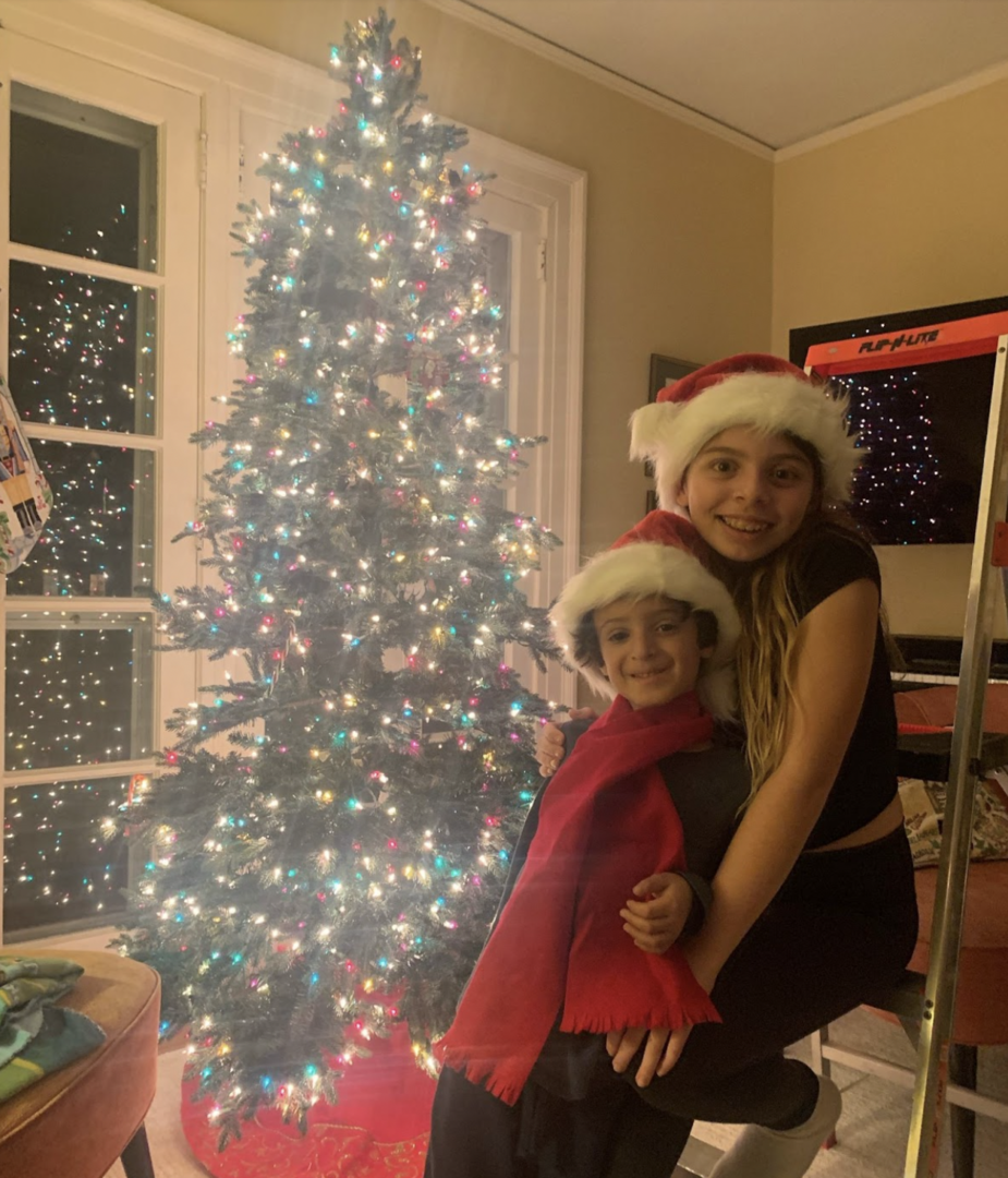 Author's two children wearing Santa hats in front of a Christmas tree