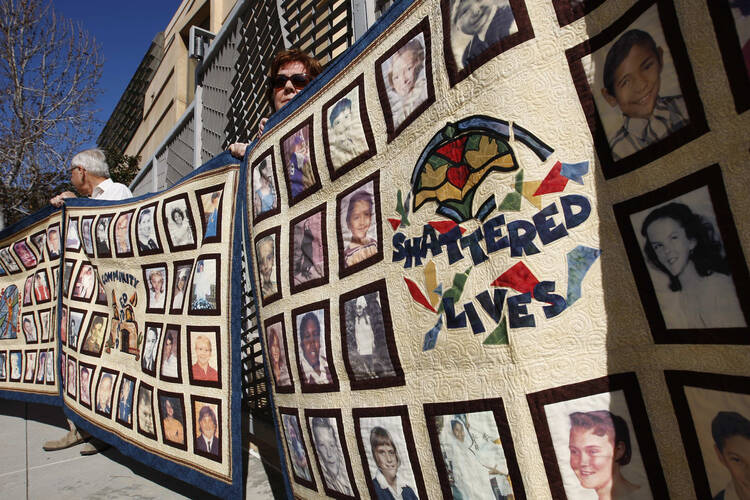 In this 2013 file photo, people stand outside the Cathedral of Our Lady of the Angels holding quilts bearing photos of victims of sexual abuse by priests of the Los Angeles Archdiocese. (CNS photo/David McNew, Reuters) 