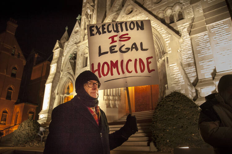 Man holds sign at vigil outside St. Louis University College Church ahead of execution of death-row inmate.