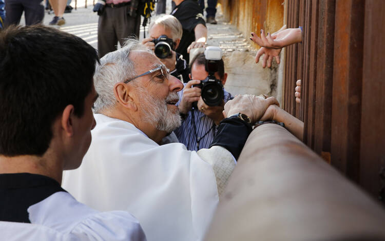U.S. Bishop Kicanas blesses people as he distributes Communion through border fence in Nogales, Ariz.