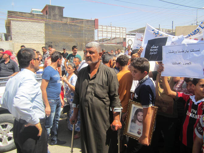 Demonstrator marches with crutches outside U.S. consulate in Iraq. (CNS photo/ Sahar Mansour)