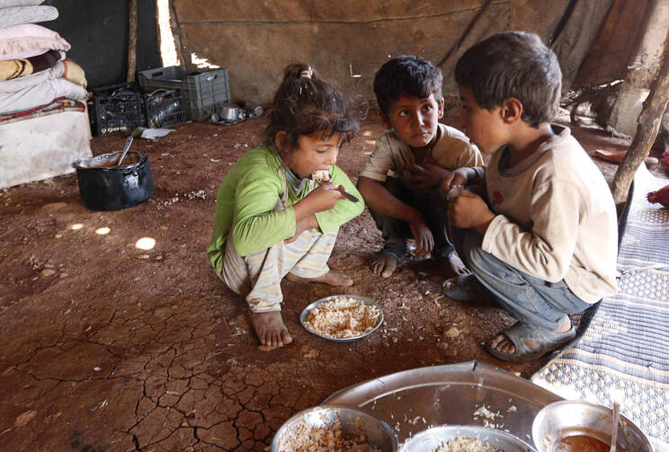Internally displaced children eat inside a tent in Aleppo, Syria, Oct. 8, 2014. (CNS photo/Jalal Al-Mamo, Reuters) 