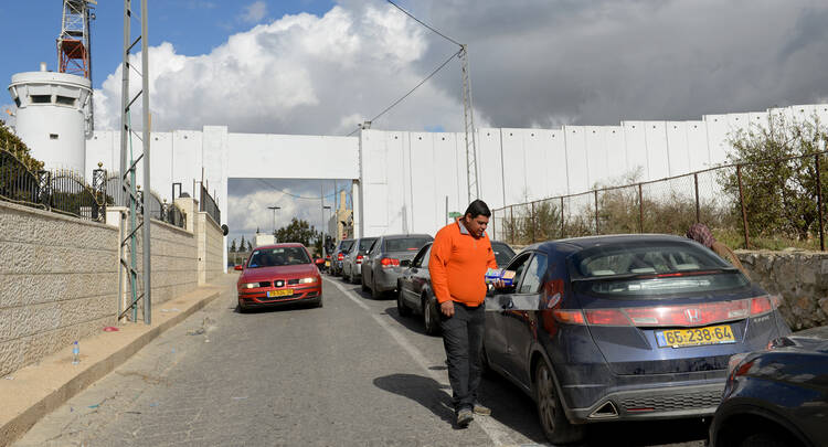 Palestinian sells souvenirs to cars passing through checkpoint at Israeli separation wall in Bethlehem.
