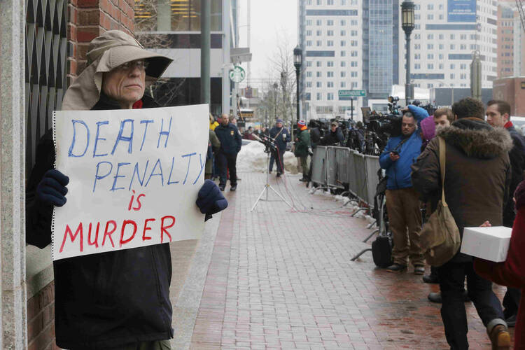 Man holds sign reading 'Death penalty is murder' outside trial of accused Boston Marathon bomber (CNS photo/Brian Snyder, Reuters)