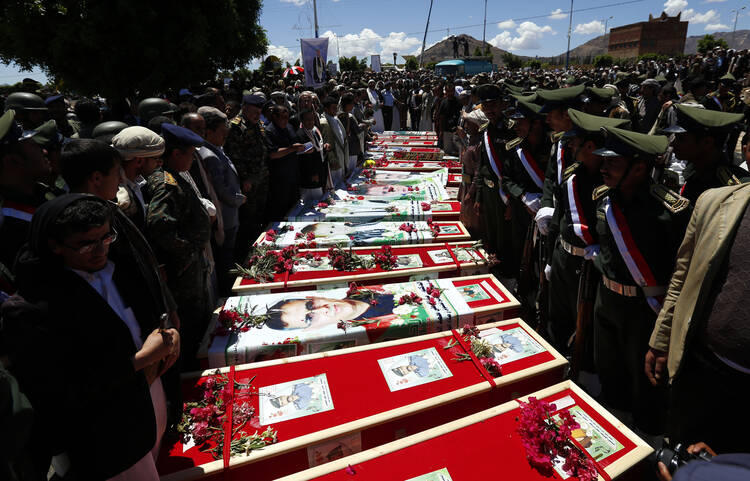 Yemeni mourners gather beside the coffins of the victims of recent suicide attacks during a funeral in Sana'a, Yemen, March 25. (CNS photo/Yahya Arhab, EPA) 
