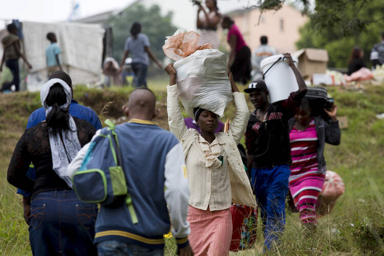 Zimbabwe nationals carry bags before boarding bus home from camp for those affected by anti-immigrant violence.