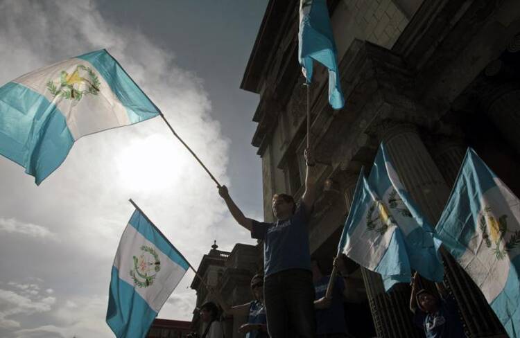 Guatemalan demonstrators wave national flags as they ask Guatemalan President Otto Perez Molina to resign during a protest in front of the National Palace of Culture in Guatemala City Aug. 22. (CNS photo/Esteban Biba, EPA) 