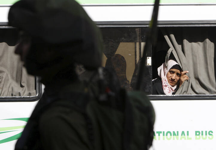 A Palestinian woman looks out a bus window during clashes between Palestinian protesters and Israeli troops in Hebron, West Bank, Oct. 4. (CNS photo/Mussa Qawasma, Reuters) 