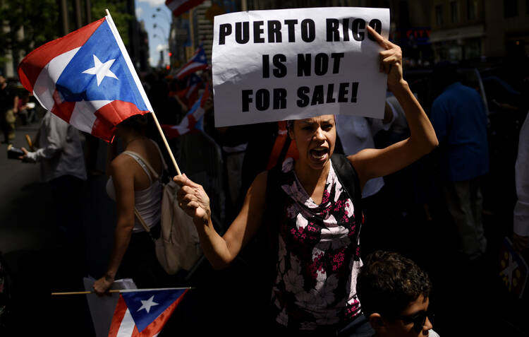 Woman protests near the office of a hedge fund manager in New York Aug. 13 over the financial crisis gripping Puerto Rico. A Senate committee held hearings Oct. 22 to discuss solutions to the crisis. (CNS photo/Justin Lane, EPA) 
