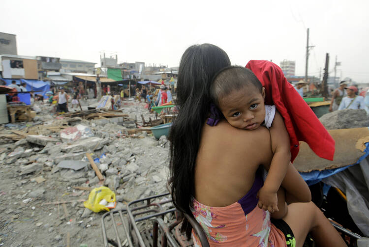 A mother holds her child while a demolition team tears down houses in 2014 during an eviction of illegal settlers in Manila, Philippines. (CNS photo/Ritchie B. Tongo, EPA) 