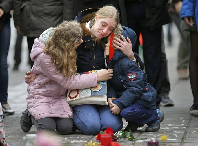 A woman consoles her children at a street memorial March 23 following bomb attacks in Brussels. Three nearly simultaneous attacks March 22 claimed the lives of dozens and injured more than 200. (CNS photo/Vincent Kessler, Reuters) 