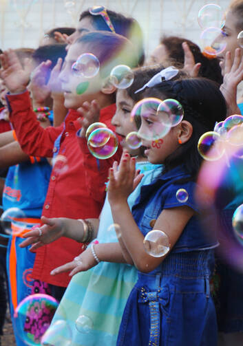 Syrian refugee children sing among floating bubbles during a graduation ceremony at the Latin Patriarchate School in Naour, Jordan, on July 11. (CNS photo/Dale Gavlak)