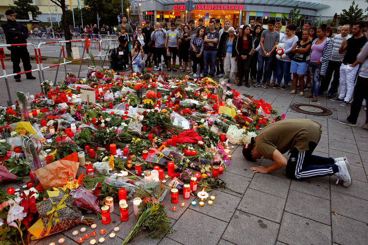 A man prays outside the Olympia shopping mall in Munich, Germany, July 23, where nine people were killed by an 18-year-old gunman. (CNS photo/Arnd Wiegmann, Reuters)