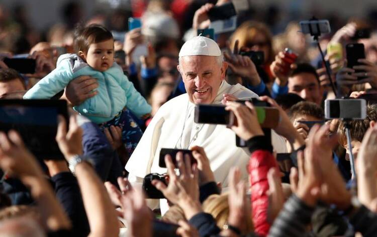 People take photos on smartphones as Pope Francis greets the crowd during his general audience in St. Peter's Square at the Vatican Oct. 12. The pope called for an immediate cease-fire in Syria so that civilians can be rescued. (CNS photo/Paul Haring)