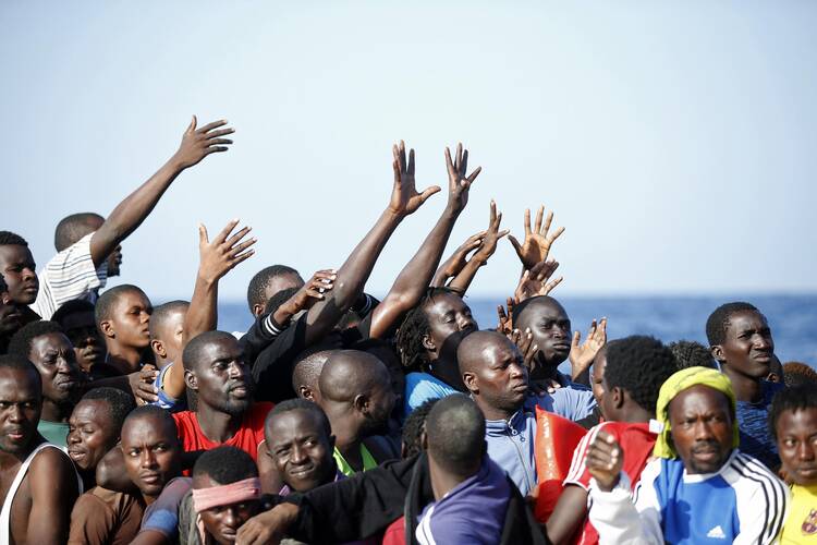 Migrants reach out from a boat during rescue operations Oct. 20 in the Mediterranean Sea. (CNS photo/Italian Red Cross via EPA)