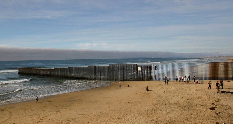 People in Tijuana, Mexico, stand next to a wall separating Mexico and the United States Dec. 10.