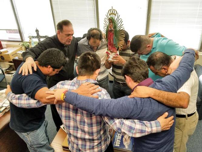 Father Jose E. Hoyos, director of the Spanish Apostolate Office of the Diocese of Arlington, Va., prays with a group of Hispanic leaders in his office on Feb. 24. (CNS photo/Mary Stachyra Lopez, Arlington Catholic Herald) 