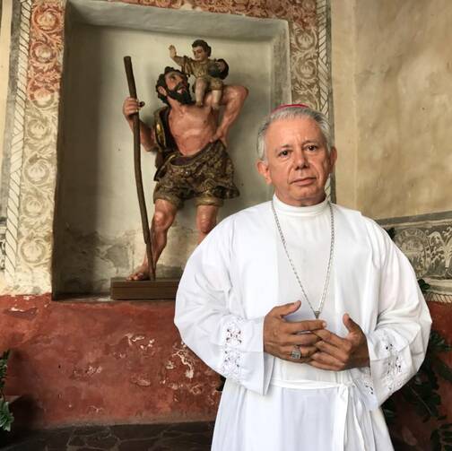 Bishop Ramon Castro Castro of Cuernavaca, Mexico, poses on March 26 in the Assumption of Mary Cathedral in front of an image of St. Christopher from the colonial period. (CNS photo/David Agren)