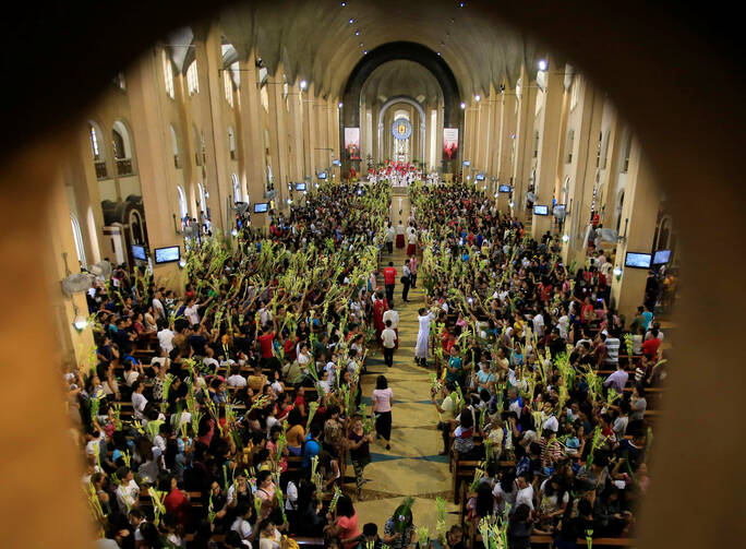 People hold palm fronds during Palm Sunday Mass on April 9 at Our Lady of Perpetual Help Church in Manila, Philippines. (CNS photo/Romeo Ranoco, Reuters)