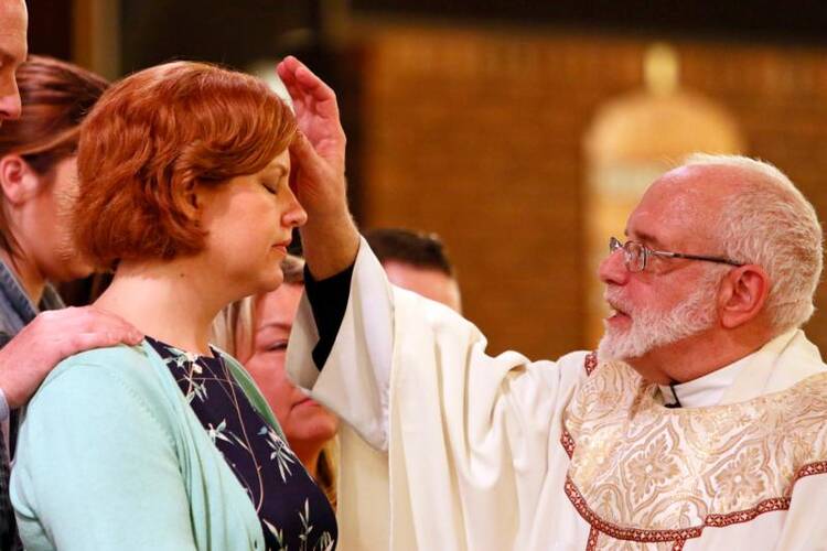 Msgr. Christopher Heller anoints Shanna Doyle with sacred chrism oil as she is confirmed during the Easter Vigil at St. Louis de Montfort Church in Sound Beach, N.Y., on April 15. (CNS photo/Gregory A. Shemitz) 