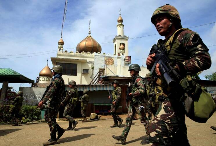 Philippine government soldiers walk past a mosque before their May 25 assault on Maute insurgents, who have taken over large parts of the town of Marawi. Residents started to evacuate Marawi after President Rodrigo Duterte imposed martial law across the entire Muslim-majority region of Mindanao. (CNS photo/Romeo Ranoco, Reuters)