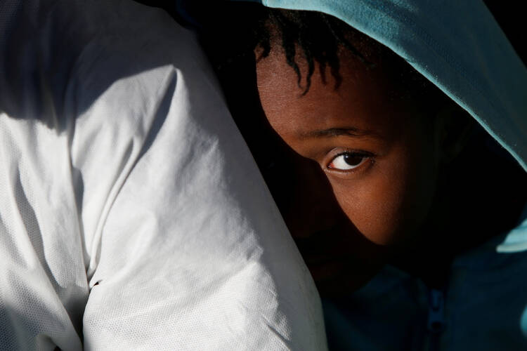 A migrant child sits on the deck of rescue ship as it arrives on April 19 in Augusta, Italy. (CNS photo/Darrin Zammit Lupi, pool via Reuters)
