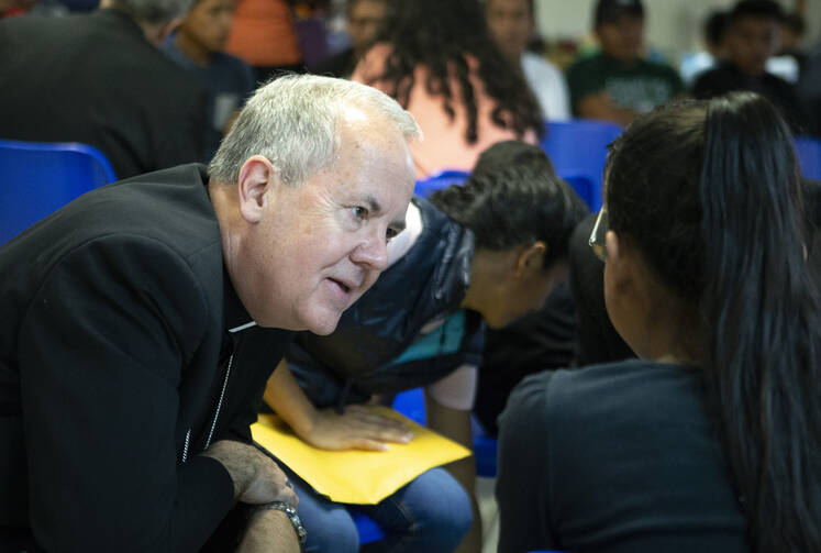 Bishop Joseph C. Bambera of Scranton, Pa., talks to an immigrant woman, recently released from U.S. custody, on July 1 at a Catholic Charities center in McAllen, Tex., as part of a fact-finding trip to the border by a delegation of U.S. bishops. (CNS photo/Chaz Muth) 