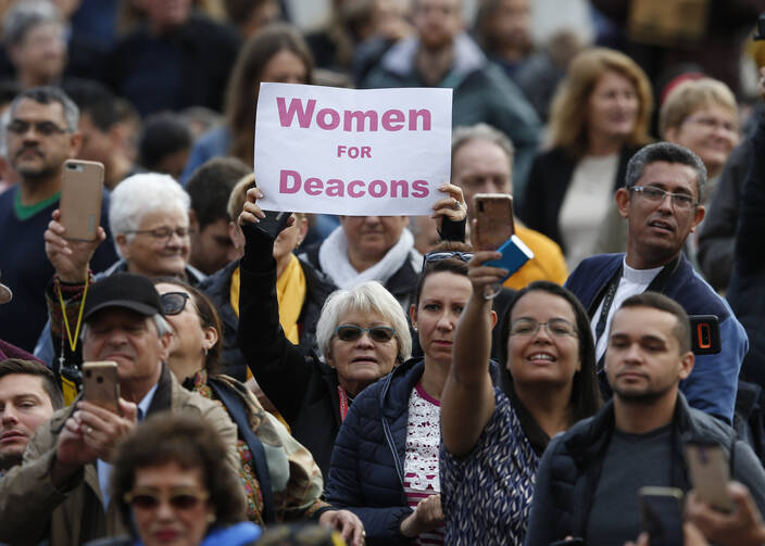 A woman holds a sign in support of women deacons as Pope Francis leads his general audience in St. Peter's Square at the Vatican on Nov. 6. (CNS photo/Paul Haring)