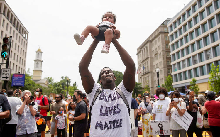 A man in Washington holds up a child during a protest against racial inequality June 6, 2020. Demonstrations continue after a white police officer in Minnesota was caught on a bystander's video May 25 pressing his knee into the neck of George Floyd, an African American, who was later pronounced dead at a hospital. (CNS photo/Eric Thayer, Reuters) 