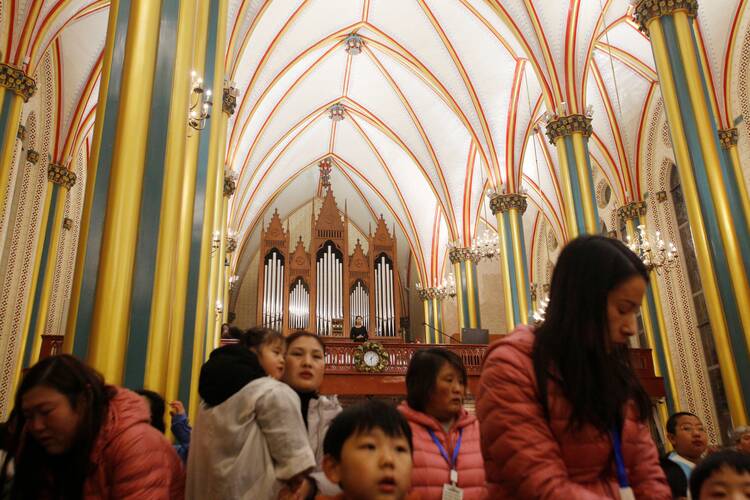worshippers attend a mass at a cathedral in china, most of the ceiling is seen in the image along with people