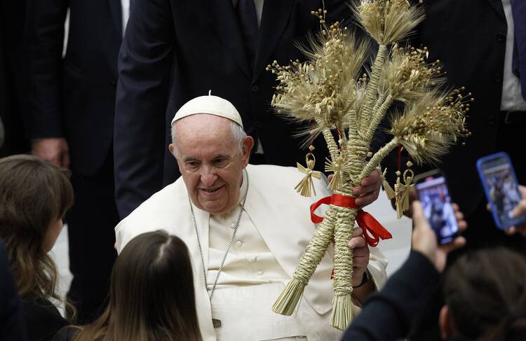 pope francis holds a gift aloft during the general audience, he is wearing his usual white