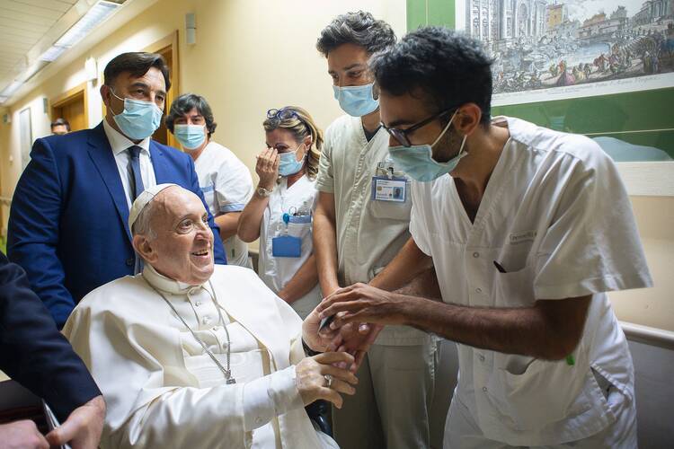 Pope Francis in wheelchair greeting hospital staff at Gemelli hospital.
