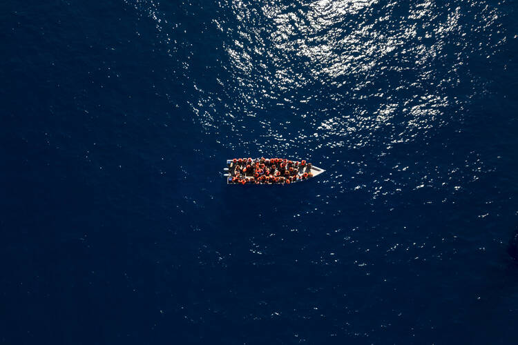 Migrants from Eritrea, Libya and Sudan sail a wooden boat before being assisted by aid workers of the Spanish NGO Open Arms, in the Mediterranean sea, about 30 miles north of Libya, Saturday, June 17, 2023. (AP Photo/Joan Mateu Parra)