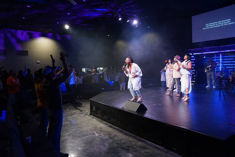 people dance in front of the stage where a worship leader leads people in song at a nondenominational church