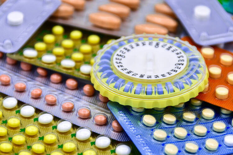 An oral contraceptive tray is seen among several packages of colorful pills on a counter.