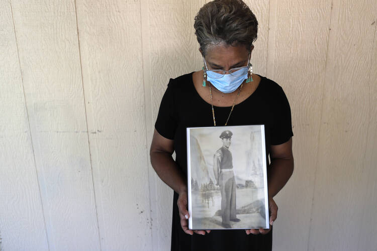 In this May 18, 2020, file photo, Belvin Jefferson White poses with a portrait of her father Saymon Jefferson at Saymon's home in Baton Rouge, La. Belvin recently lost both her father and her uncle, Willie Lee Jefferson, to COVID-19. (AP Photo/Gerald Herbert, File)