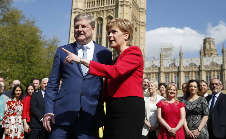 Scotland's First Minister Nicola Sturgeon, with lawmaker Angus Robertson an SNP member of the UK Parliament, speak to the media outside the Palace of Westminster in London, Wednesday, April 19, 2017. British Prime Minister Theresa May on Tuesday called for a snap June 8 general election, seeking to strengthen her hand in European Union exit talks and tighten her grip on a fractious Conservative Party. (AP Photo/Alastair Grant)