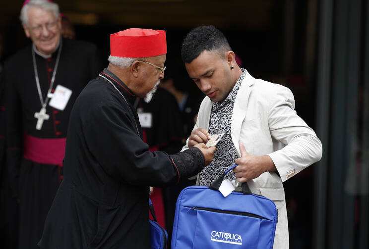  Ethiopian Cardinal Berhaneyesus Souraphiel of Addis Ababa checks out the name badge of Nathanael Lamataki, a youth delegate from the French territory of New Caledonia in the South Pacific, as they leave a session of the Synod of Bishops on young people, the faith and vocational discernment at the Vatican Oct. 5. (CNS photo/Paul Haring) 
