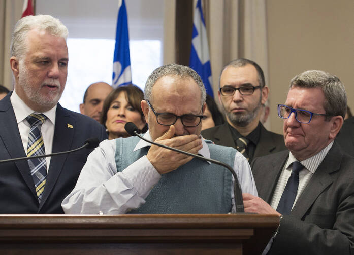 Mohamed Labidi, the vice-president of the mosque where an attack happened, is comforted by Quebec Premier Philippe Couillard, left, and Quebec City mayor Regis Labeaume, right, during a news conference on Jan. 30 about the fatal shooting at the Quebec Islamic Cultural Centre on Sunday. (Jacques Boissinot/The Canadian Press via AP)