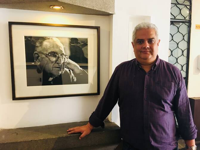 Nery Rodenas, director of the Human Rights Office of the Archdiocese of Guatemala, stands beside a portrait of Bishop Juan José Gerardi. (Jackie McVicar)