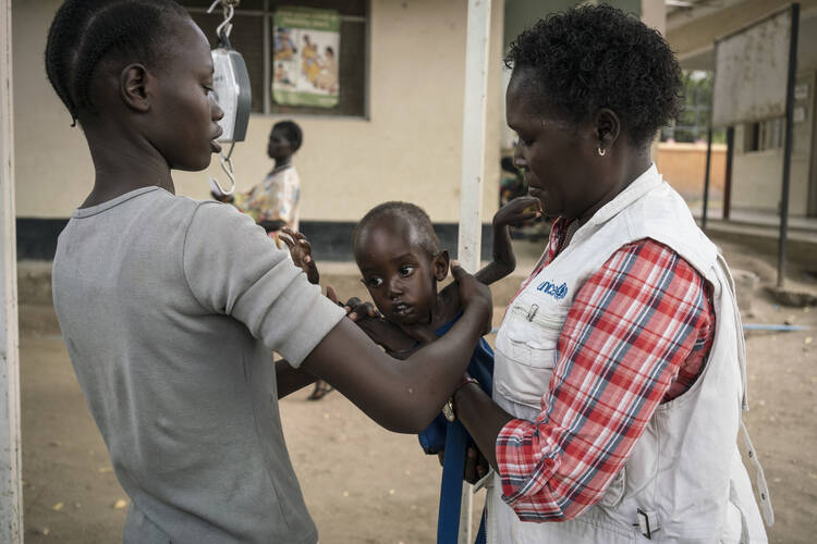 In this photo taken on Tuesday, March 14, 2017, a mother, left, takes hold of her son after he was weighed and found to be suffering from severe acute malnutrition, at Al Sabbah Children's Hospital in Juba, South Sudan. (Mackenzie Knowles-Coursin/UNICEF via AP)