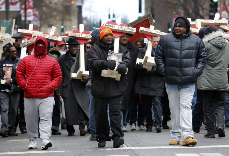 People carry crosses with names of victims of gun violence during a Dec. 31 march in downtown Chicago. Hundreds of people joined the march to remember those who died by gun violence in 2016 (CNS photo/Karen Callaway, Catholic New World).