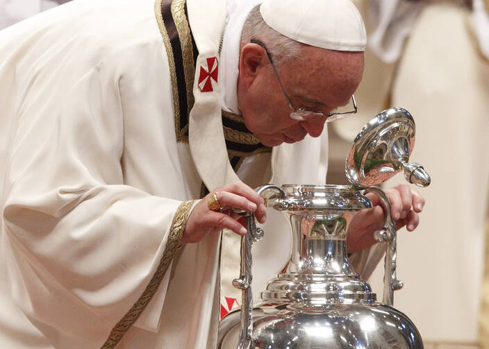 Pope Francis breathes over chrism oil, a gesture symbolizing the infusion of the Holy Spirit, during Holy Thursday chrism Mass in St. Peter's Basilica at the Vatican. 