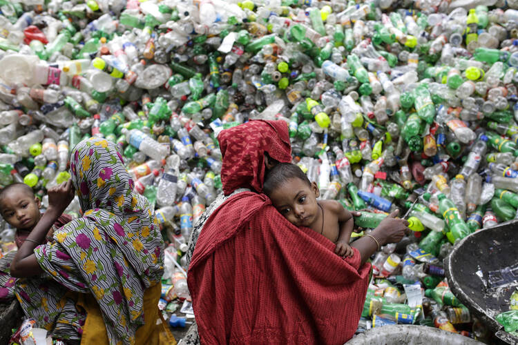 Women hold children while sifting through plastic bottles at a recycling factory in Mohammadpur, Bangladesh, Oct. 26. (CNS photo/Abir Abdullah, EPA)