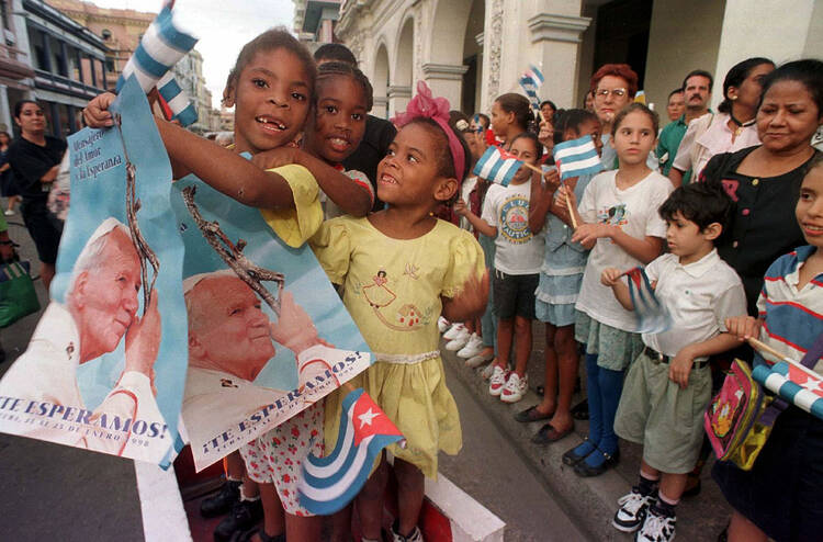 Children holding Cuban flags and images of Pope John Paul II line a Havana street Jan. 20 staking out positions where they might get a glance of the pontiff on his arrival to Cuba Jan. 21, 1998. (CNS photo/Alyssa Banta)
