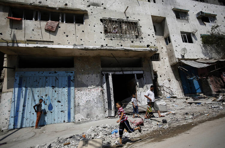 A Palestinian boy runs next to destroyed buildings in Gaza City Aug. 28. (CNS photo/Mohammed Saber, EPA) 
