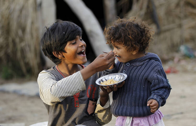 A boy feeds his sister in a slum on the outskirts of Islamabad March 30. The World Bank and global faith leaders are joining together to end extreme poverty around the world by 2030. (CNS photo/Caren Firouz, Reuters)