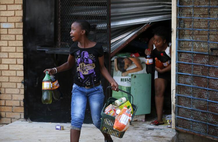 Locals run with items from a shop in Soweto, South Africa, Jan. 22. Local media reported that violence broke out Jan. 19 after a 14-year-old South African was allegedly shot dead by a foreign shop owner (CNS photo/Siphiwe Sibeko, Reuters).