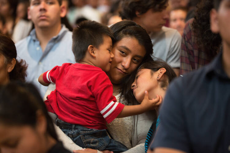 A woman holds onto her children during a special Mass in Los Angeles in July 2014 honoring immigrants (CNS photo/Victor Aleman, Vida-Nueva.com).